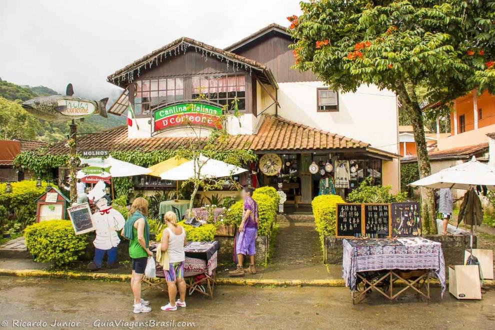 Imagem de turistas em frente a uma cantina na Vila de Maringá em Visconde de Mauá.